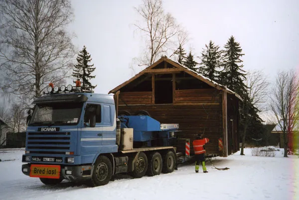Ett mindre trähus lastat på trailer i snö